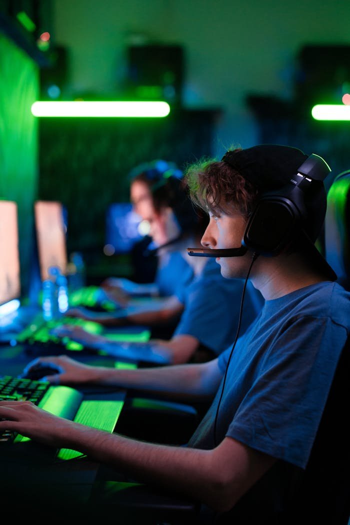 Intense gaming session with teens in a cybersport competition, illuminated by vibrant green lighting.